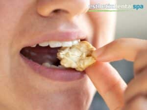 Close-up of a person eating a crunchy nut, showing how food texture and diet affect dental enamel and gum health