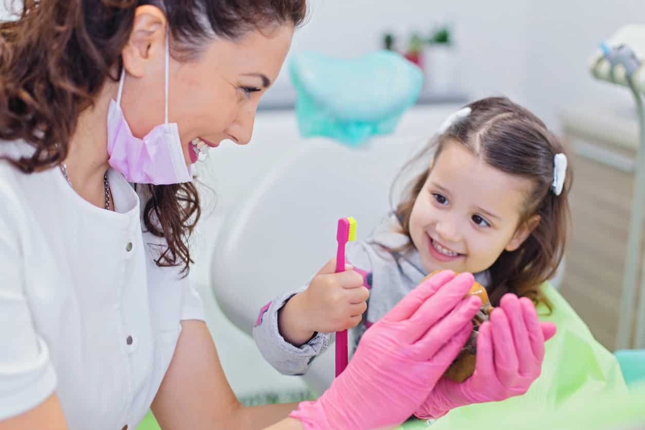 dentist helping a young girl to understand hygiene