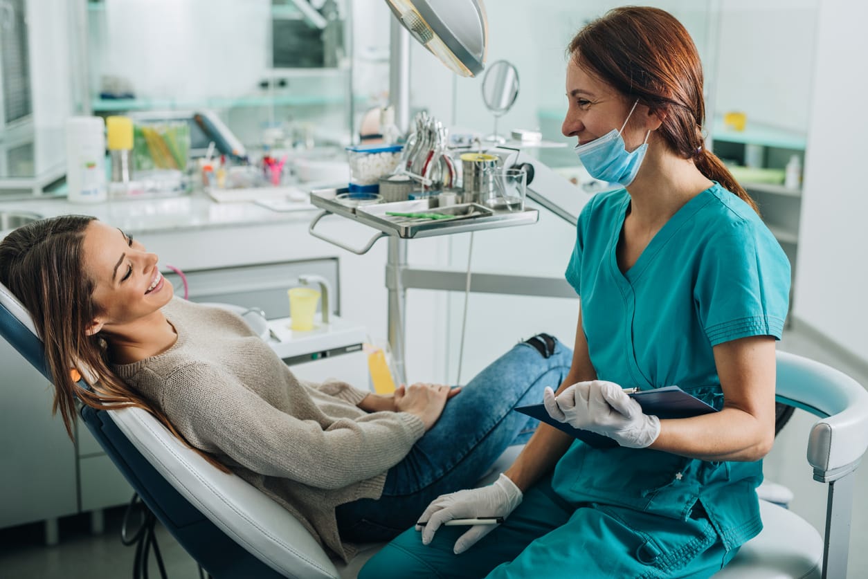 Young smiling woman talking to her dentist at dentist's office.