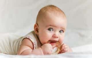 baby girl chewing on teething toy
