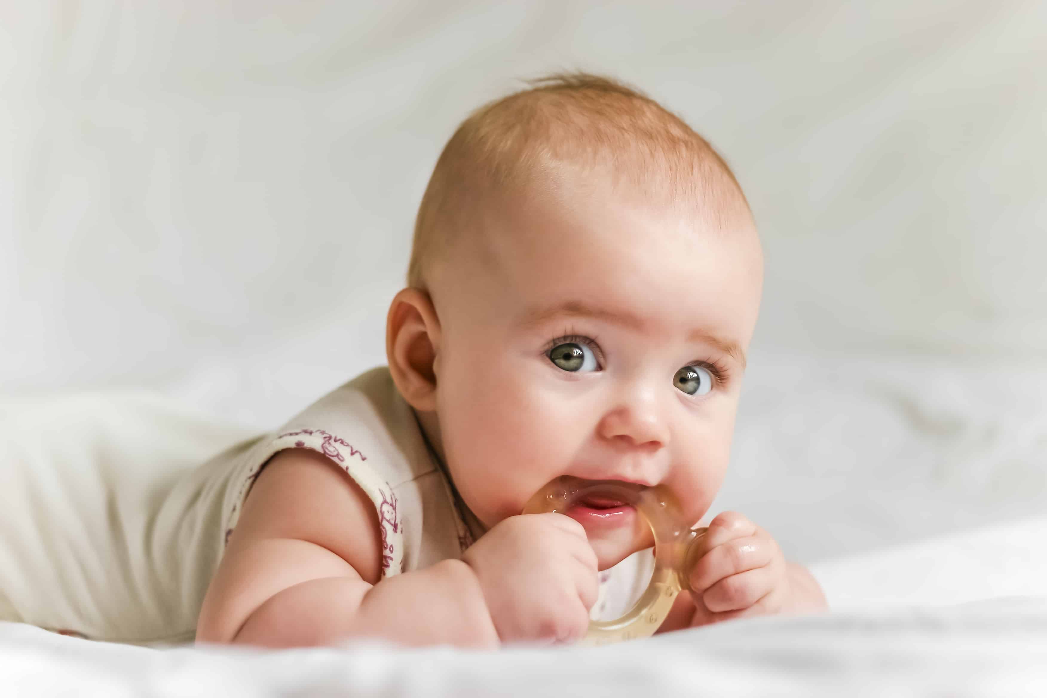 baby girl chewing on teething toy