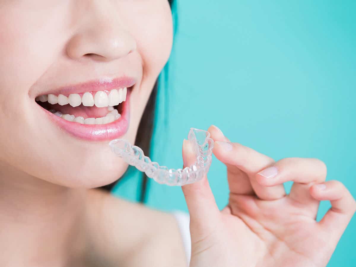 Woman Inserting Her Invisalign Tray For Teeth Straightening In New York