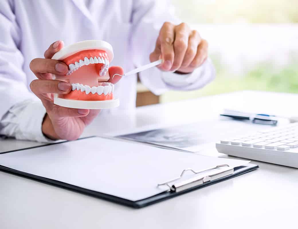 Dentist Explaining Dental Implants With A Dental Model