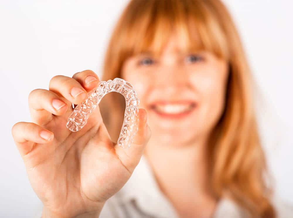 Lady holding Invisalign aligners