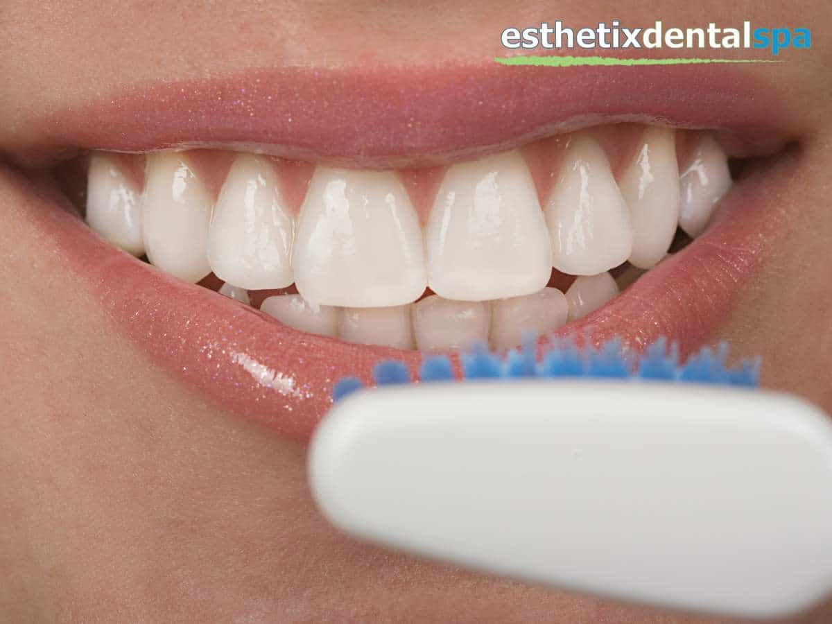 Close-up of a smile with white teeth, possibly after a cosmetic dentistry makeover, with a toothbrush in the foreground