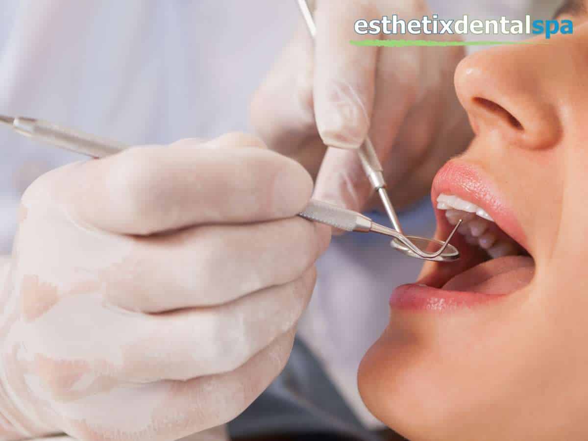 Dentist performing endodontic therapy on a patient's open mouth, with dental instruments and gloved hands, indicative of a root canal treatment.